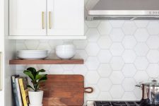 a navy and white kitchen with a white hexagon tile backsplash, an open shelf and stainless steel appliances is cool