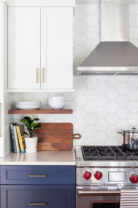 a navy and white kitchen with a white hexagon tile backsplash, an open shelf and stainless steel appliances is cool