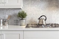 a neutral kitchen with a lovely silver small hex tile backsplash and stainless steel appliances that create a cohesive look