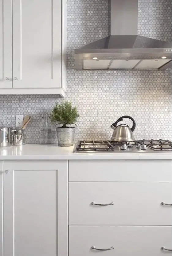 a neutral kitchen with a lovely silver small hex tile backsplash and stainless steel appliances that create a cohesive look