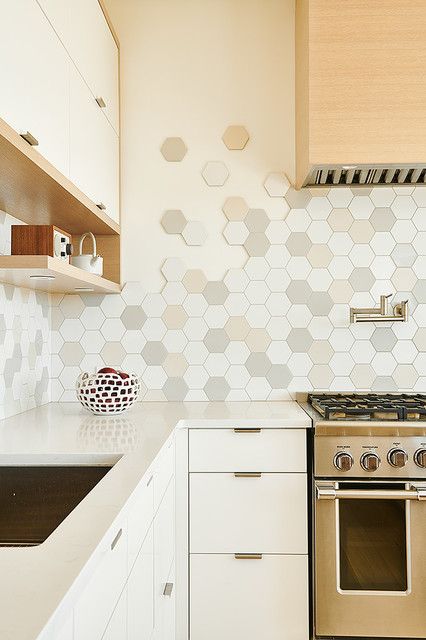 A neutral kitchen with a stained hood, neutral stone countertops, an eye catching hexagon tile backsplash