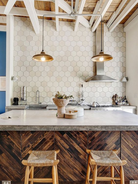 a quirky kitchen with rich-stained cabinets, concrete countertops and an extended hexagon tile backsplash plus pendant lamps