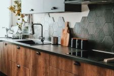 a rich-stained kitchen with black countertops, black upper cabinets and a black hexagon tile backsplash