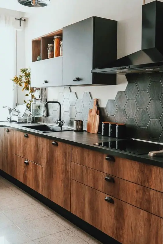 A rich stained kitchen with black countertops, black upper cabinets and a black hexagon tile backsplash