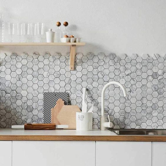 a sleek white kitchen with a grey marble hex tile backsplash, an open shelf and white fixtures is lovely