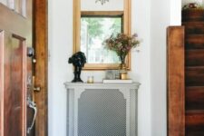 a small radiator with an elegant grey cover with a perforated screen as a console table with books and decor is a cool idea