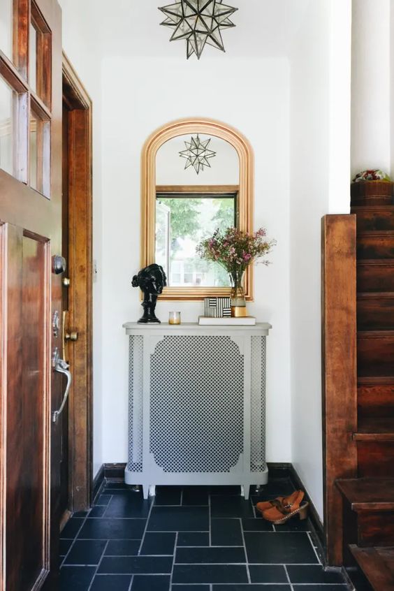 a small radiator with an elegant grey cover with a perforated screen as a console table with books and decor is a cool idea