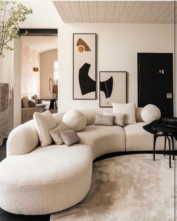 A stylish and contrasting living room with a white boucle curved sofa, a black table and eye catchy artwork on the wall
