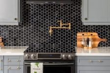 a stylish grey farmhouse kitchen with white countertops and a black hex tile backsplash plus a black hood looks very refined