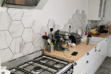 a white Nordic kitchen with butcherblock countertps and a grey hexagon tile backsplash plus butcherblock countertops