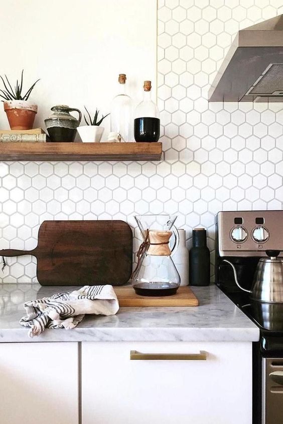 a white Nordic kitchen with white countertops and a white hexagon tile backsplash plus an open shelf and stainless steel appliances