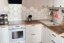 a white Scandinavina kitchen with greige walls, a white hexagon tile backsplash and butcherblock countertops is amazing