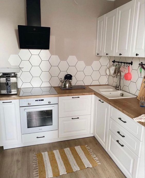a white Scandinavina kitchen with greige walls, a white hexagon tile backsplash and butcherblock countertops is amazing