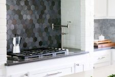 a white kitchen with a dark hexagon tile backsplash and grey countertops plus grey marble tiles is cool