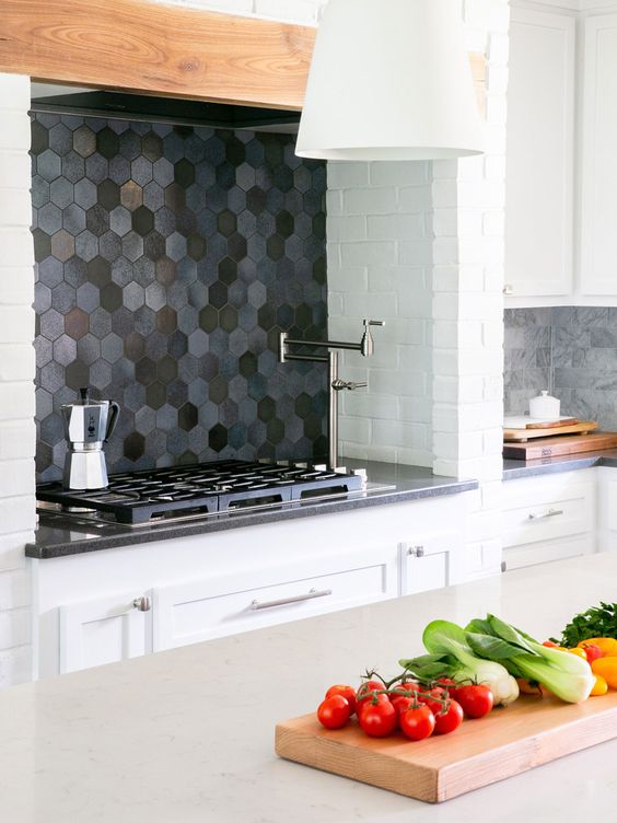 a white kitchen with a dark hexagon tile backsplash and grey countertops plus grey marble tiles is cool
