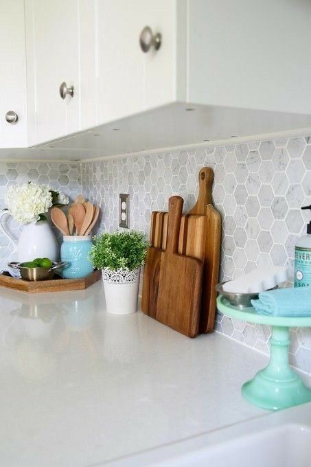 a white kitchen with a white marble hexagon tile backsplash and white stone countertops is a timeless idea