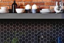 black hex tile backsplash with white grout and exposed red brick to make your kitchen stand out