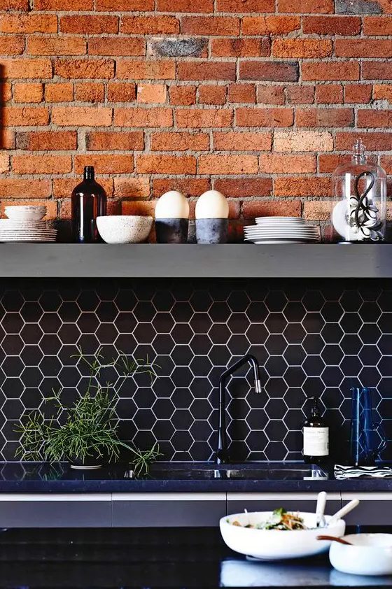 black hex tile backsplash with white grout and exposed red brick to make your kitchen stand out