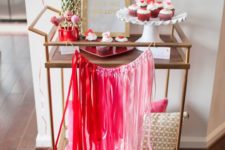 colorful Valentine bar cart styling with an ombre tassel bunting and hot pink blooms
