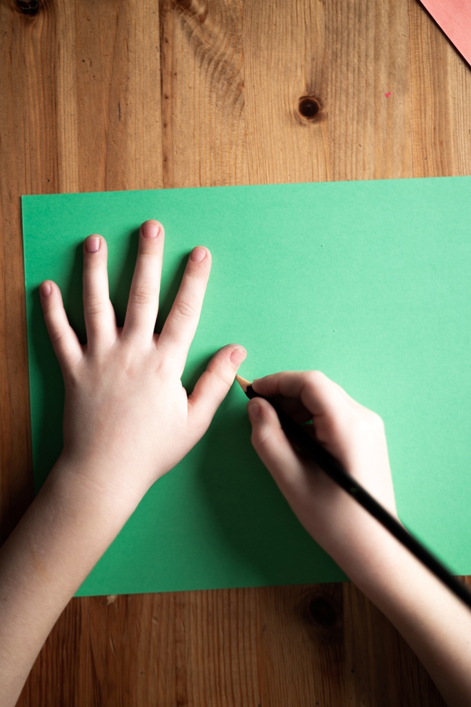 Take a green sheet of paper and trace your kid’s hand