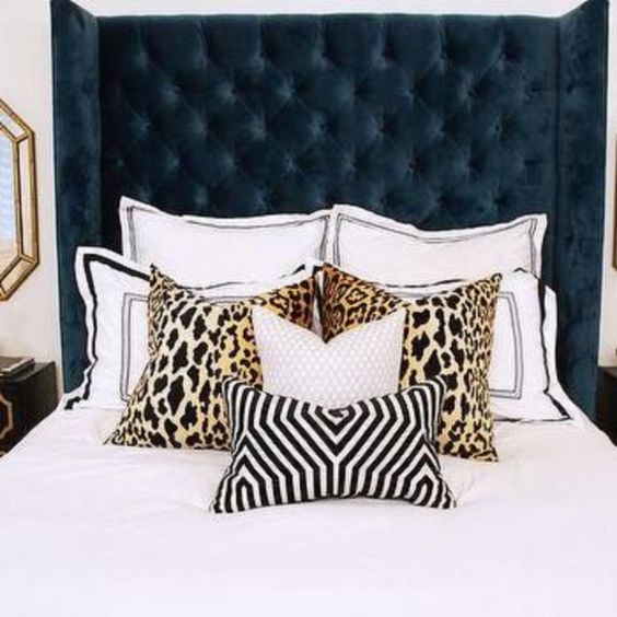 a navy wingback tufted headboard and printed pillows make a bold statement in the bedroom