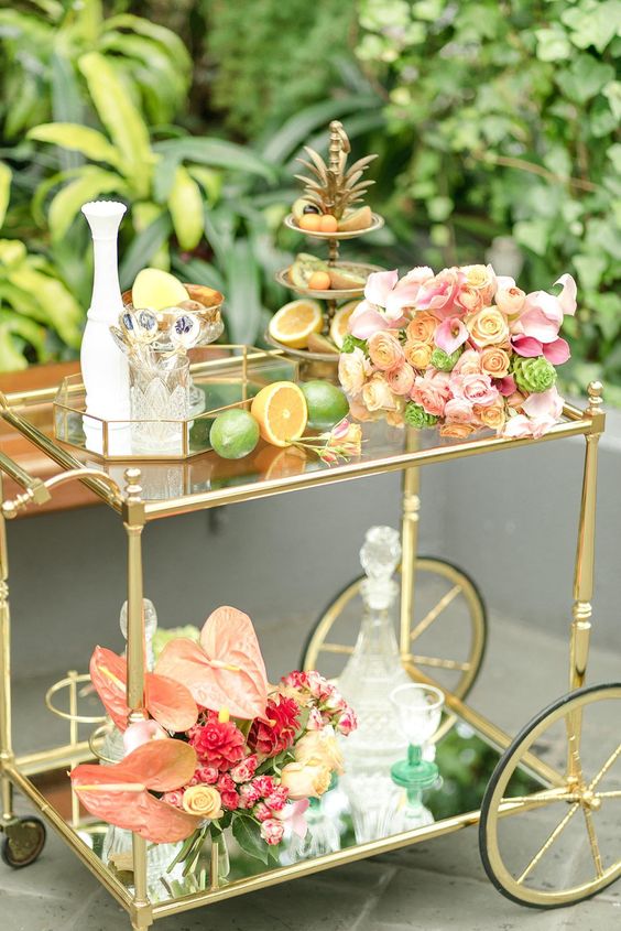 a luxurious tropical bar cart with citrus, lush blooms, greenery and a fruit stand