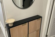 an IKEA Hemnes shoe cabinet in black, with reeded wooden panels and gold pulls is a very elegant piece for any entryway