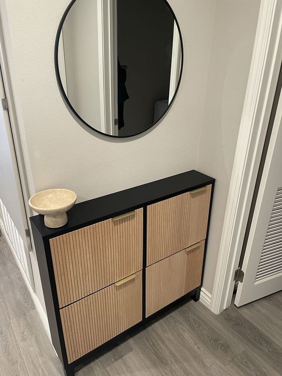 an IKEA Hemnes shoe cabinet in black, with reeded wooden panels and gold pulls is a very elegant piece for any entryway
