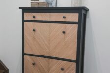 an IKEA Hemnes shoe cabinet painted black, clad with wood and with black knobs is a cool piece with a modern twist