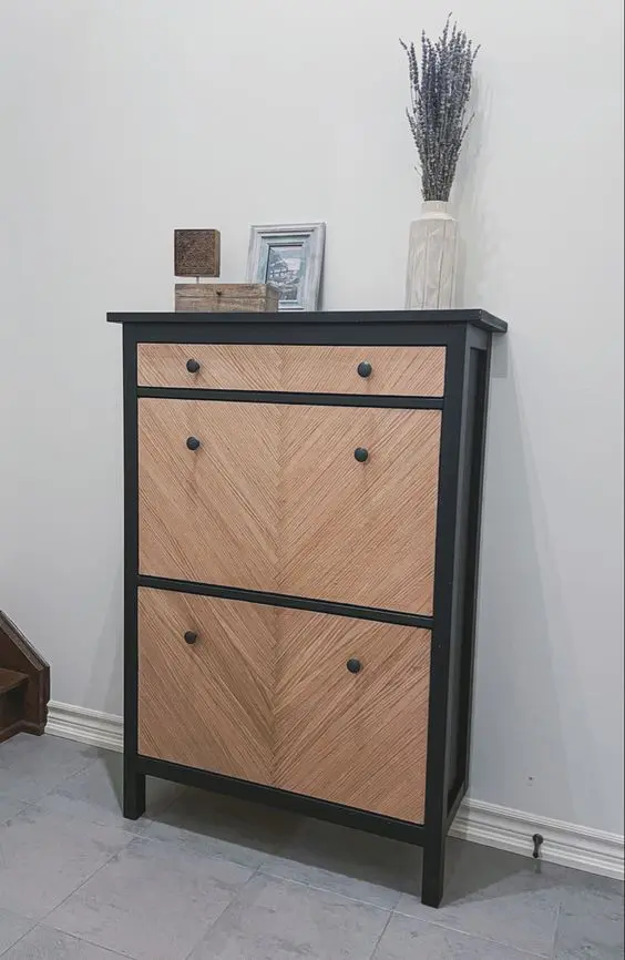 an IKEA Hemnes shoe cabinet painted black, clad with wood and with black knobs is a cool piece with a modern twist