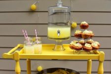 03 a bright yellow drink station with lemonade and a large metal bowl with lemons inside