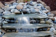 03 a natural looking waterfall done with large rocks and with pebbles around will bring a frehs feel to your front yard