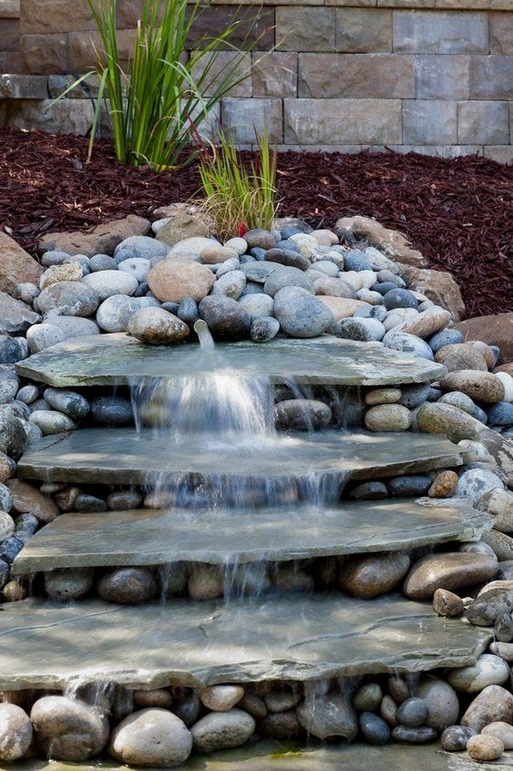 a natural looking waterfall done with large rocks and with pebbles around will bring a frehs feel to your front yard