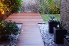 07 a modern and elegant wooden garden path with a matching deck surrounded with pebbles and lights along it