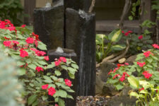 07 a modern fountain of large dark stones nestled in a bed of impatiens by the front door
