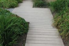 10 a neutral wooden plank path surrounded with shrubs and greenery for a beach cottage garden