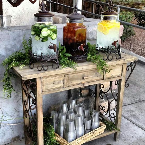 a vintage meets rustic drink bar of wood with forged decor, a basket with plastic cups and some chic tanks