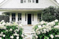 17 a white picket fence with lush white blooms and greenery all around make the front yard dreamy