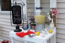 19 a white vintage-inspired drink station with potted greenery, some bottles in a bucket with ice cubes and a chalkboard sign