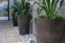 21 a pathway lined up with large pots with greenery and pebbles on the ground for an ultra-modern space