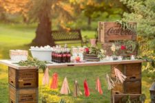 25 a vintage industrial drink station built of crates and a tabletop, decorated with greenery and a colorful tassel garland