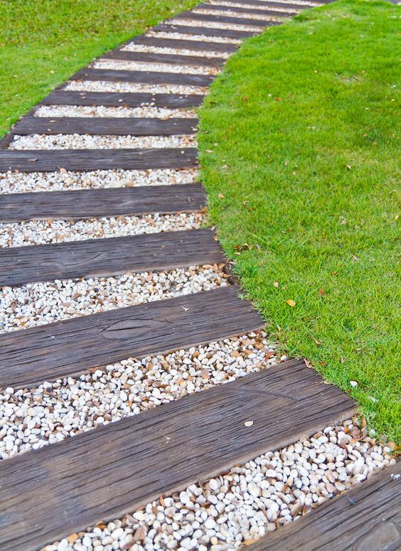 this curved walkway is comprised of alternating weathered wood and white pebble segments