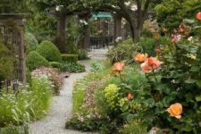 a colorful and bold garden with lots of blooms and trees, with gravel pathways and some wooden furniture