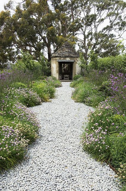 a garden with greenery and purple blooms, a gravel path are a cool combo for any romantic garden