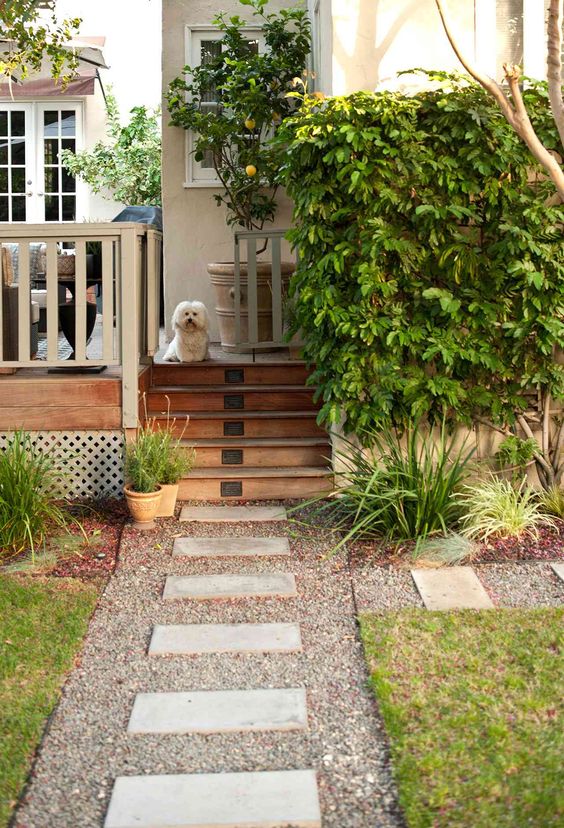 a laconic and modern garden with a green lawn, a gravel path with stepping stones, potted greenery and a living edge