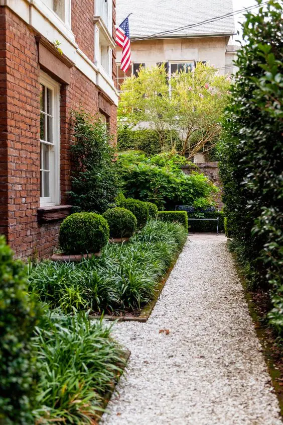 a modern and elegant side yard with a grave path, greenery and shrubs is a stylish solution for a modern home