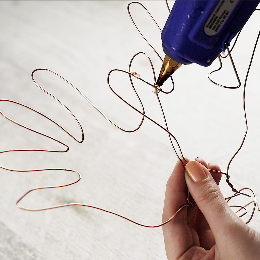 Remove the wire hands form the nails and hot glue them to each other.