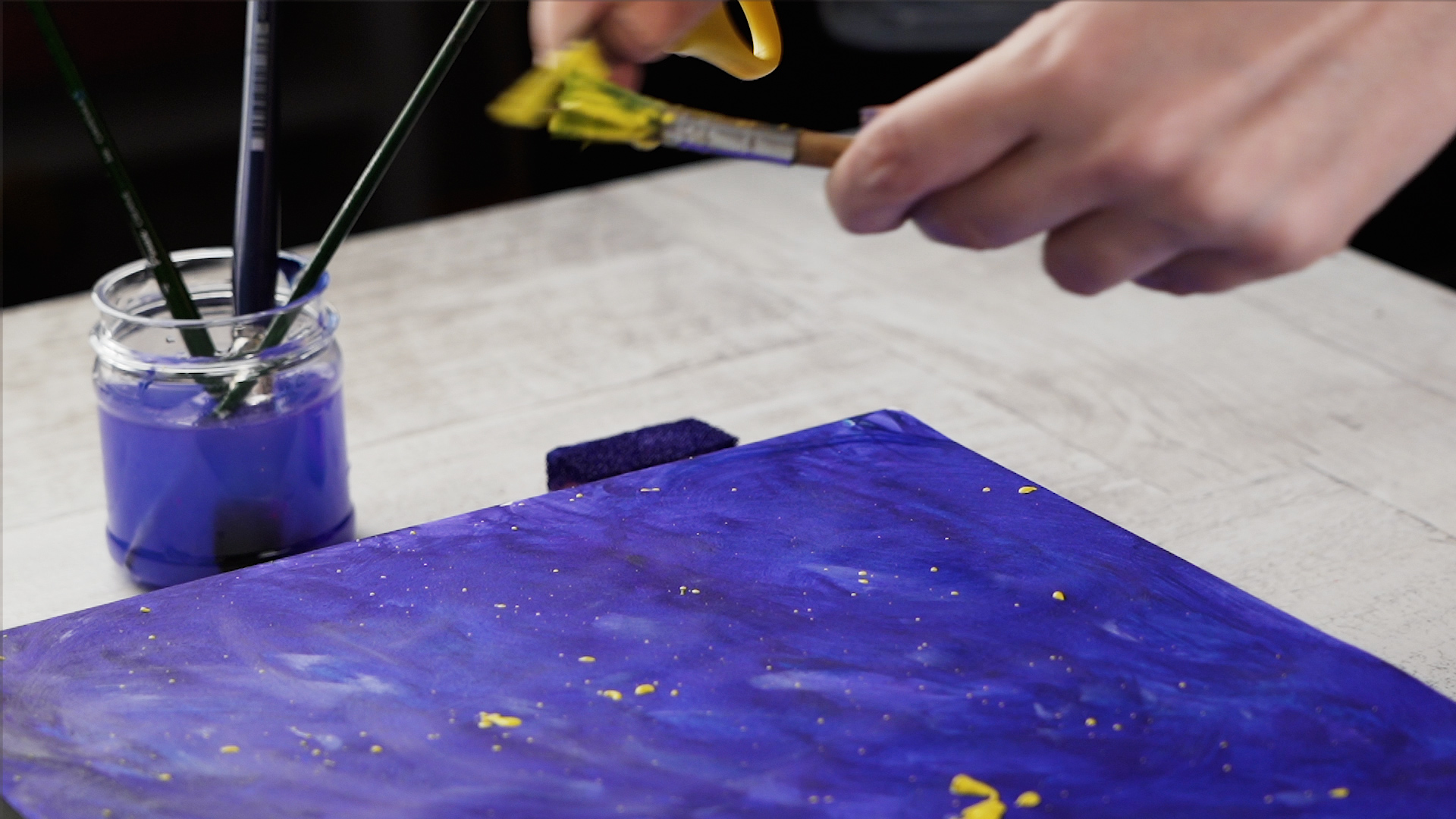 Make some yellow splashes on the paper using two brushes and yellow paint.