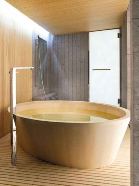 a minimalist light-colored wooden bathtub with a plank wooden floor, matching walls and metal fixtures