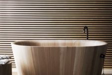 12 a polished free-standing wooden bathtub in a bathroom clad with wooden planks for a minimalist and natural space